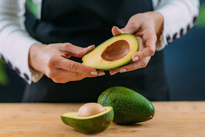 Cutting fresh, organic avocado, superfood rich in monosaturated fat, vitamins, minerals, fibers and phytonutrients